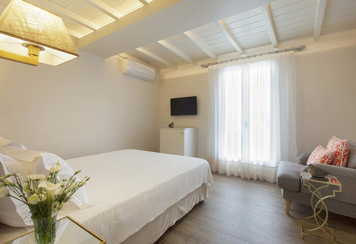 Despotiko Hotel room in Mykonos Town for gay honeymoon. Modern design, white linens, and a cozy seating area. Popular gay hotel in Chora.