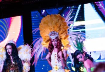 Drag queens perform at Posh Club, Lisbon. Vibrant costumes, feathers, and makeup create a lively atmosphere for gay men's travel in Portugal.