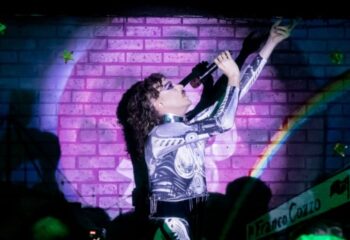 Drag queen performing at Pride of Footscray Melbourne. Singer in futuristic costume on stage with microphone. Gay travel advice.