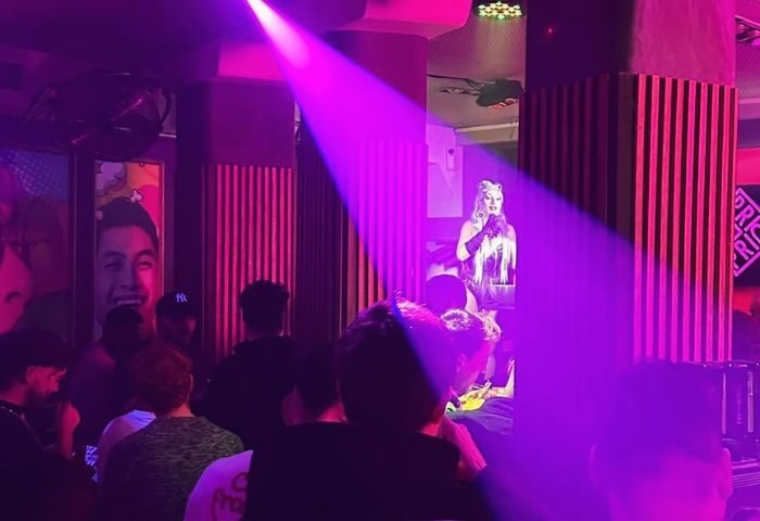 Madrid's Prima S-Bar gay bar: Drag queen performs under purple lights for a crowd. Nightlife scene, gay travel destination.
