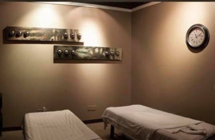 Prince Men's Spa massage room. Two massage tables with white linens, wall art, and a clock. Gay men's travel advice for relaxation.