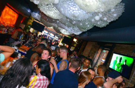 Progress Bar Chicago gay party nights. Crowded gay bar scene with diverse crowd, bar, and unique ceiling decor. Nightlife for gay men travel.