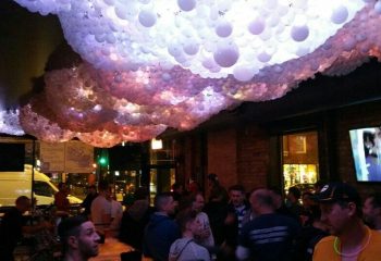 Gay party nights in Chicago bar. Crowd of men under balloon decorations. Nightlife scene in a gay bar.