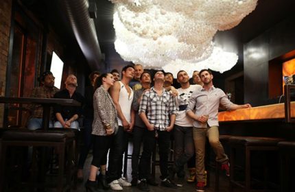 Gay party nights in Chicago: Group of people looking up at a unique cloud-like light fixture in a bar. Nightlife scene.
