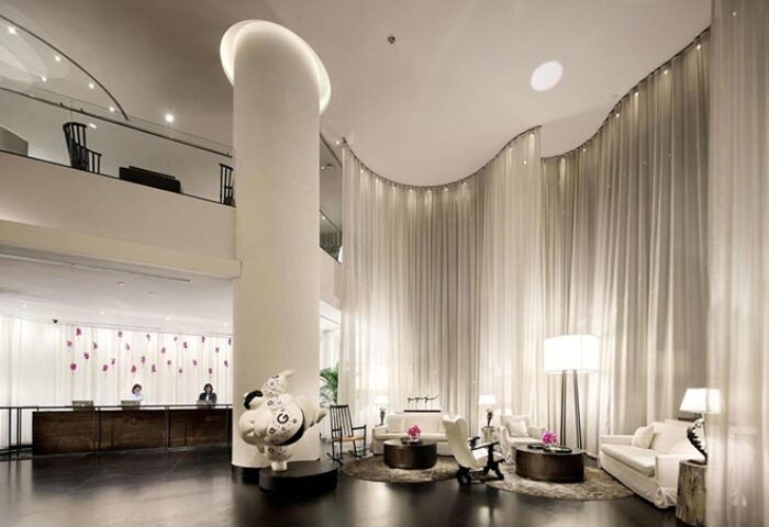 Pullman Bangkok Hotel G lobby interior. Modern design with sheer curtains, seating area, and unique art. Gay travel in Bangkok, Thailand.