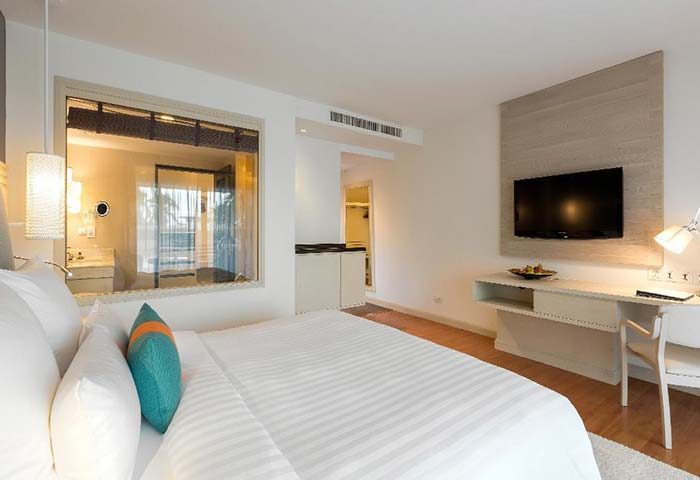 Pullman Phuket Panwa Beach Resort room. Modern design, white bedding, desk, and TV. Ideal for gay men's travel in Phuket, Thailand.