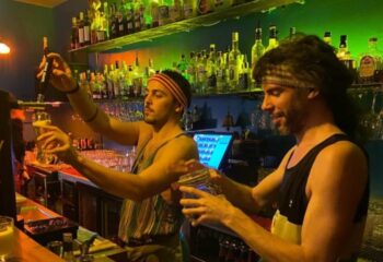 Purex Clube Lisbon: Two bartenders serving drinks at a gay bar in Lisbon. Nightlife scene with drinks and friendly service. Gay travel.