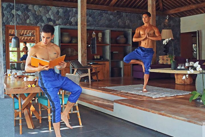 Gay travel: Two shirtless men at Purist Villas, Ubud, Bali. One reads, the other does yoga. Luxury gay-friendly resort.