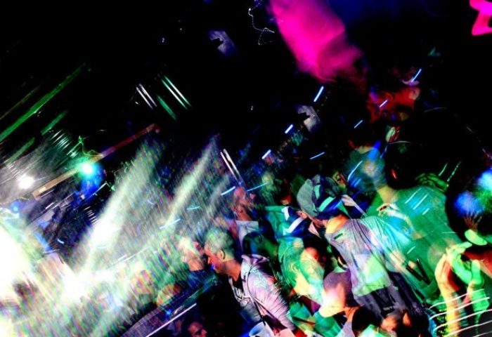 QClub Milan gay party scene. Blurry image of a crowded dance floor with colorful lights. Gay nightlife in Milan, Italy. Men dancing.
