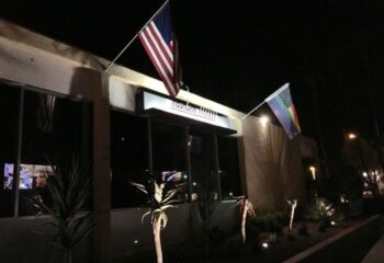 QUADZ Location: Building exterior at night with American and rainbow flags. Gay travel destination for gay men.