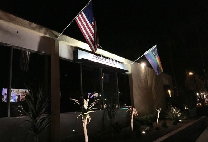 QUADZ Location: Building exterior at night with American and rainbow flags. Gay travel destination for gay men.