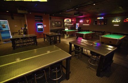Quadz Video Bar interior, Las Vegas. Pool tables, tables with stools, and neon signs. Gay bar for men's travel advice.