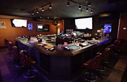 Interior of Quadz Video Bar in Las Vegas, a gay bar featuring a long bar with stools, TVs, and a wide selection of drinks. Nightlife.