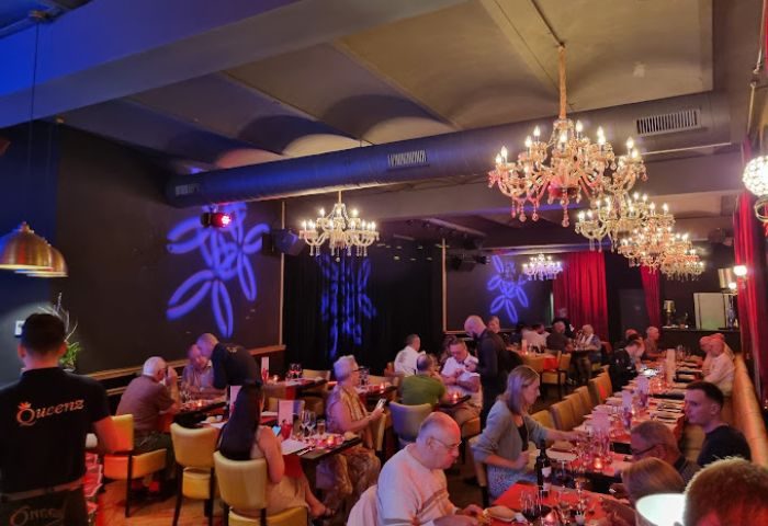 Queenz Cabaret Show gay bar in Sitges. Patrons dine under chandeliers. Gay travel destination for shows, drinks, and nightlife.