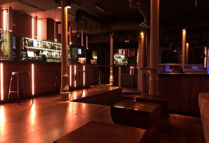 Madrid gay bar interior. Rick's bar features a stylish, dimly lit space with wooden floors, bar stools, and modern lighting.