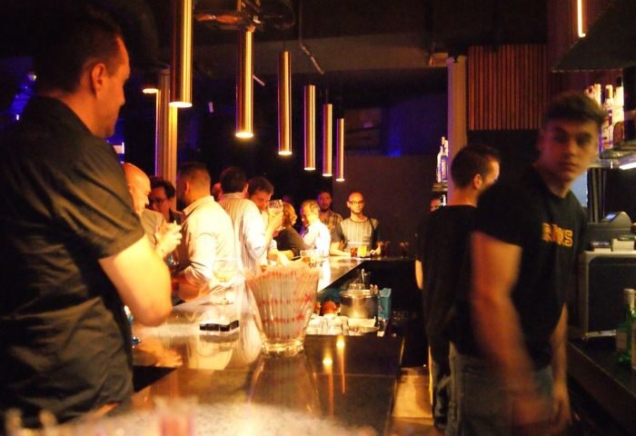 Gay bar in Madrid: Rick's bar interior view. Men at the bar, enjoying drinks. Nightlife scene, travel advice for gay men in Madrid, Spain.