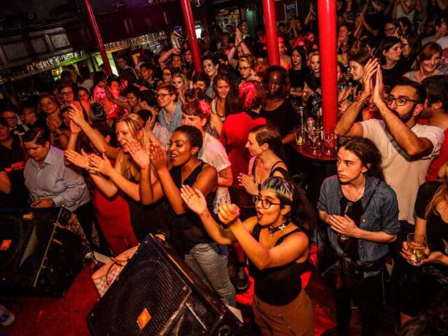 Crowd at RVT (Royal Vauxhall Tavern) gay bar in London. People are clapping and cheering. Nightlife scene, LGBTQ+ travel advice.