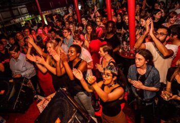Crowd at RVT (Royal Vauxhall Tavern) gay bar in London. People are clapping and cheering. Nightlife scene, LGBTQ+ travel advice.