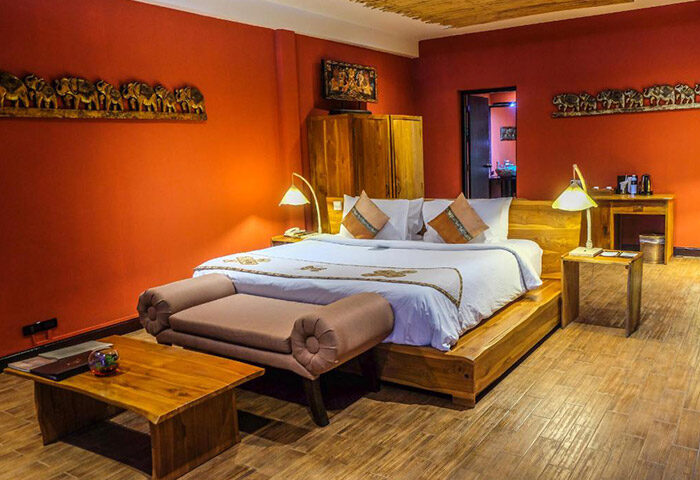 Kupu Kupu Phangan Beach Villas' Real Thai design. Luxury gay hotel room with wooden bed, orange walls, and elephant decor. L’Occitane spa.