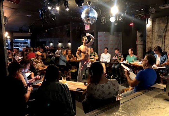 Rebar Chelsea, New York. Male dancer performs for a sketching class. Gay bar with a disco ball and a crowd of people. Gay travel advice.