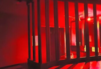 Interior of Reds Cruising Club, a gay cruise club in Gran Canaria, featuring a dark room with red lighting and a wooden partition.