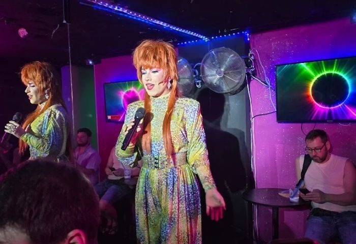 Drag queen performing at Reina, a popular gay bar in Madrid. The performer is wearing a colorful dress and holding a microphone.