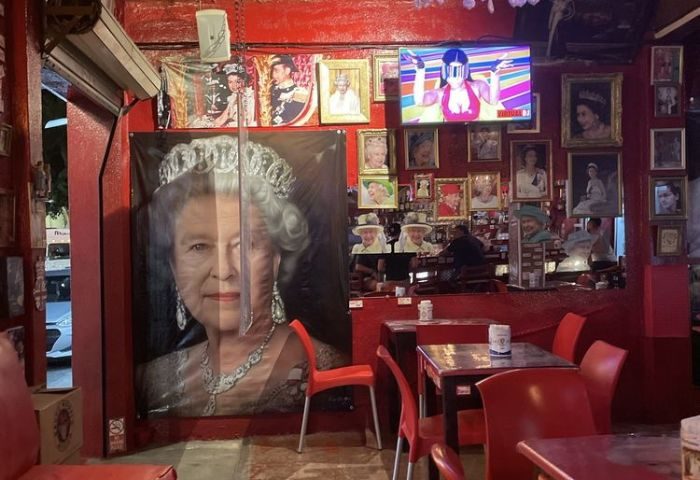 Reinas Bar, gay place in Puerto Vallarta. Red interior with Queen Elizabeth themed decor, portraits, and TV screen. Gay travel guide.