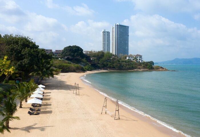 Renaissance Pattaya Resort beachfront view. Perfect gay honeymoon hotel. Sandy beach, turquoise water, palm trees, and modern buildings.
