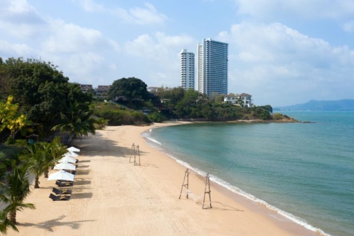 Renaissance Pattaya Resort beachfront view. Perfect gay honeymoon hotel. Sandy beach, turquoise water, palm trees, and modern buildings.
