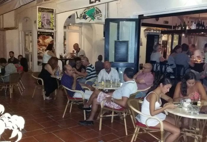 La Esquina gay bar in Torremolinos. People at tables outside the popular gay bar, enjoying drinks. Gay travel advice.