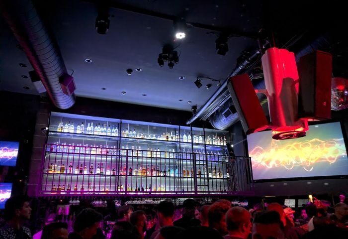 Inside Revolver Bar: A lively gay bar scene with a well-stocked bar, modern lighting, and a crowd of patrons enjoying the atmosphere.