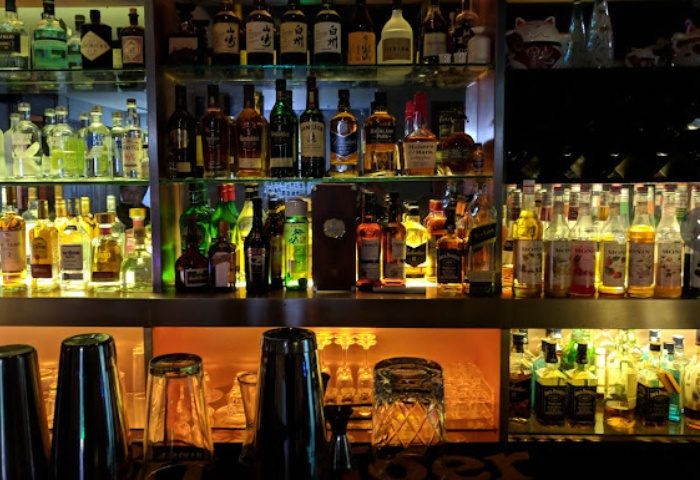 Shanghai bar scene: Shelves stocked with liquor bottles, glasses, and cocktail shakers. A vibrant nightlife spot for gay travelers.