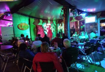 Ricky's Cabaret Bar, a gay bar in Gran Canaria. Patrons watch a drag show on stage. Nightlife scene, gay travel advice.