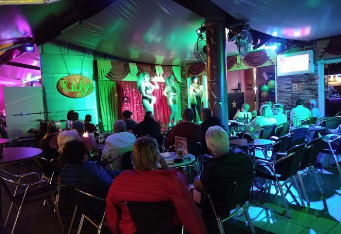 Ricky's Cabaret Bar, a gay bar in Gran Canaria. Patrons watch a drag show on stage. Nightlife scene, gay travel advice.