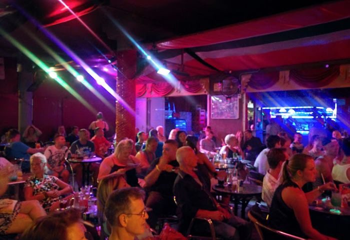 Ricky's Cabaret Bar, a gay bar in Gran Canaria. A crowd sits at tables under colorful stage lights, enjoying the lively atmosphere.
