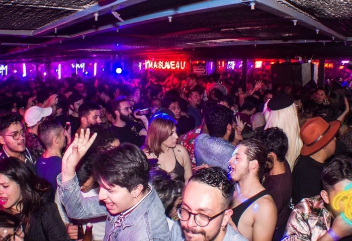 Crowded Rico Club gay bar in Mexico. Men and women dance under neon lights. Gay nightlife travel advice.