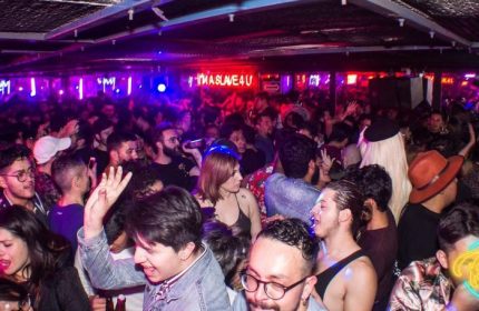 Crowded Rico Club gay bar in Mexico. Men and women dance under neon lights. Gay nightlife travel advice.