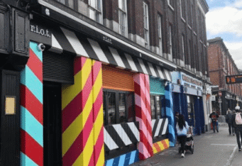 Dublin's Riot Gay Bar exterior. Colorful striped facade with black and white awning. A vibrant spot for gay men's travel in Ireland.
