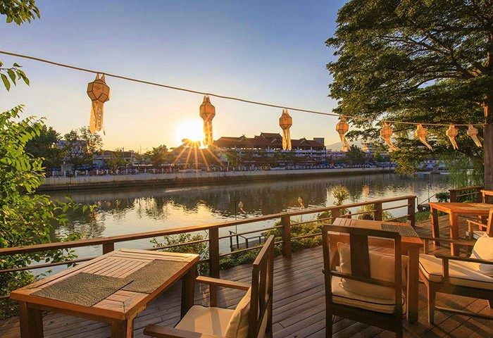 Sala Lanna Chiang Mai, a riverside gay-friendly hotel. Sunset view from the deck, with lanterns strung above the Ping River in Thailand.
