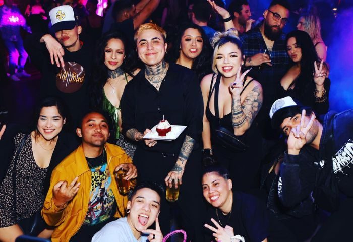 Robertson Nightclub experience: A group of diverse, smiling people pose at a gay-friendly nightlife spot, some holding drinks and a cupcake.