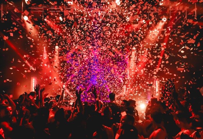 Melbourne gay nightlife: Rock City party scene. Confetti rains down on a crowd of revelers under red lights. Exciting gay travel experience.