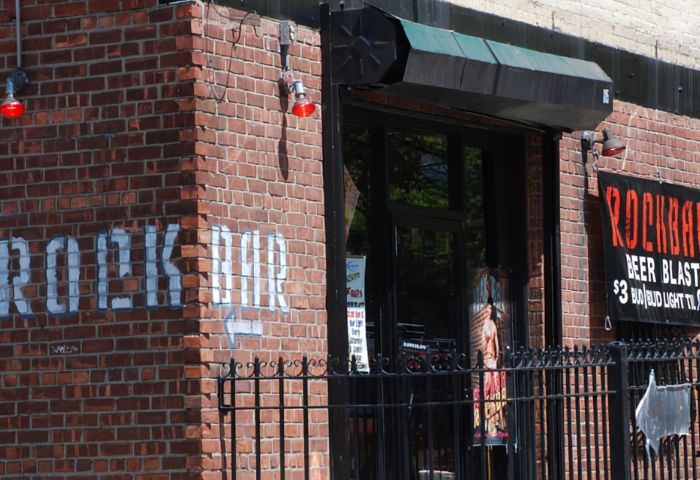 Rockbar NYC entrance. Brick building with Rock Bar painted on the side. Gay bar in New York City, travel advice.