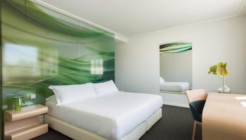 Room Mate Oscar Madrid bedroom with white linens, green accents, desk, and mirror. Best gay hotel in Chueca for this year's update.