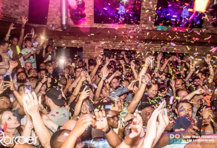 Crowd at Roscoe's Tavern, a popular gay bar in Chicago, Illinois. Confetti falling, people dancing with hands raised, phones in the air.