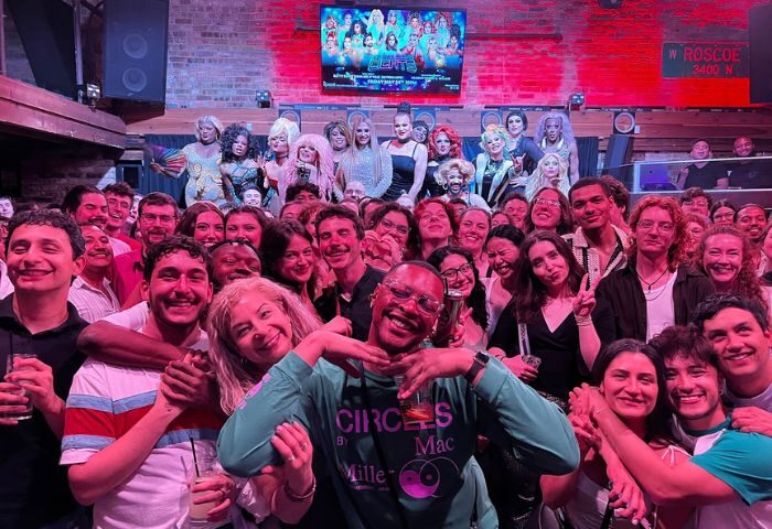 Crowd at Roscoe's Tavern, a popular gay bar in Chicago. Drag queens on stage, patrons smiling. A vibrant LGBTQ+ nightlife scene.