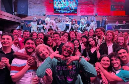 Crowd at Roscoe's Tavern, a popular gay bar in Chicago. Drag queens on stage, patrons smiling. A vibrant LGBTQ+ nightlife scene.