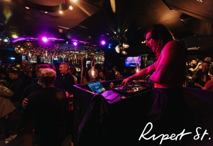 Rupert Street Bar, Soho: DJ spinning at a cool gay bar. Nightlife scene with a lively crowd enjoying the music and drinks.