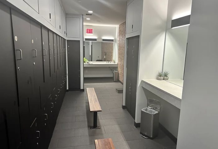 Locker room at Russian and Turkish Baths in New York. Benches, lockers, and a sink are visible. Gay travel advice.