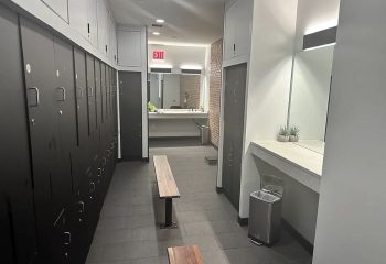 Locker room at Russian and Turkish Baths in New York. Benches, lockers, and a sink are visible. Gay travel advice.