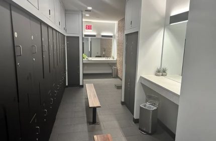 Locker room at Russian and Turkish Baths in New York. Benches, lockers, and a sink are visible. Gay travel advice.